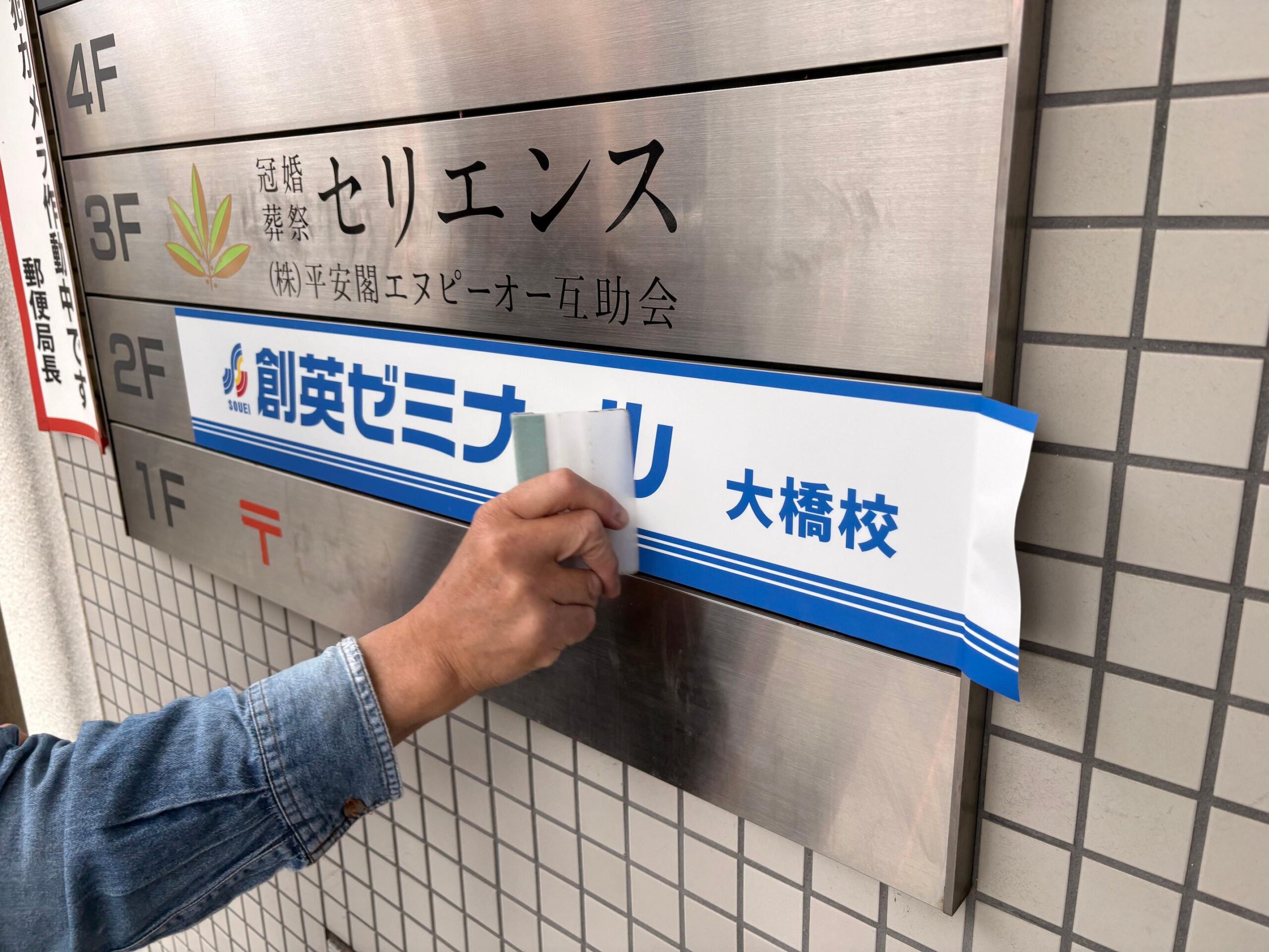 今回の施工では、ビルのフロア案内板に貼られていた白シートで隠されていた既存の表示シートを剥がし、新たにインクジェット出力で製作したサインシートを施工しました。2