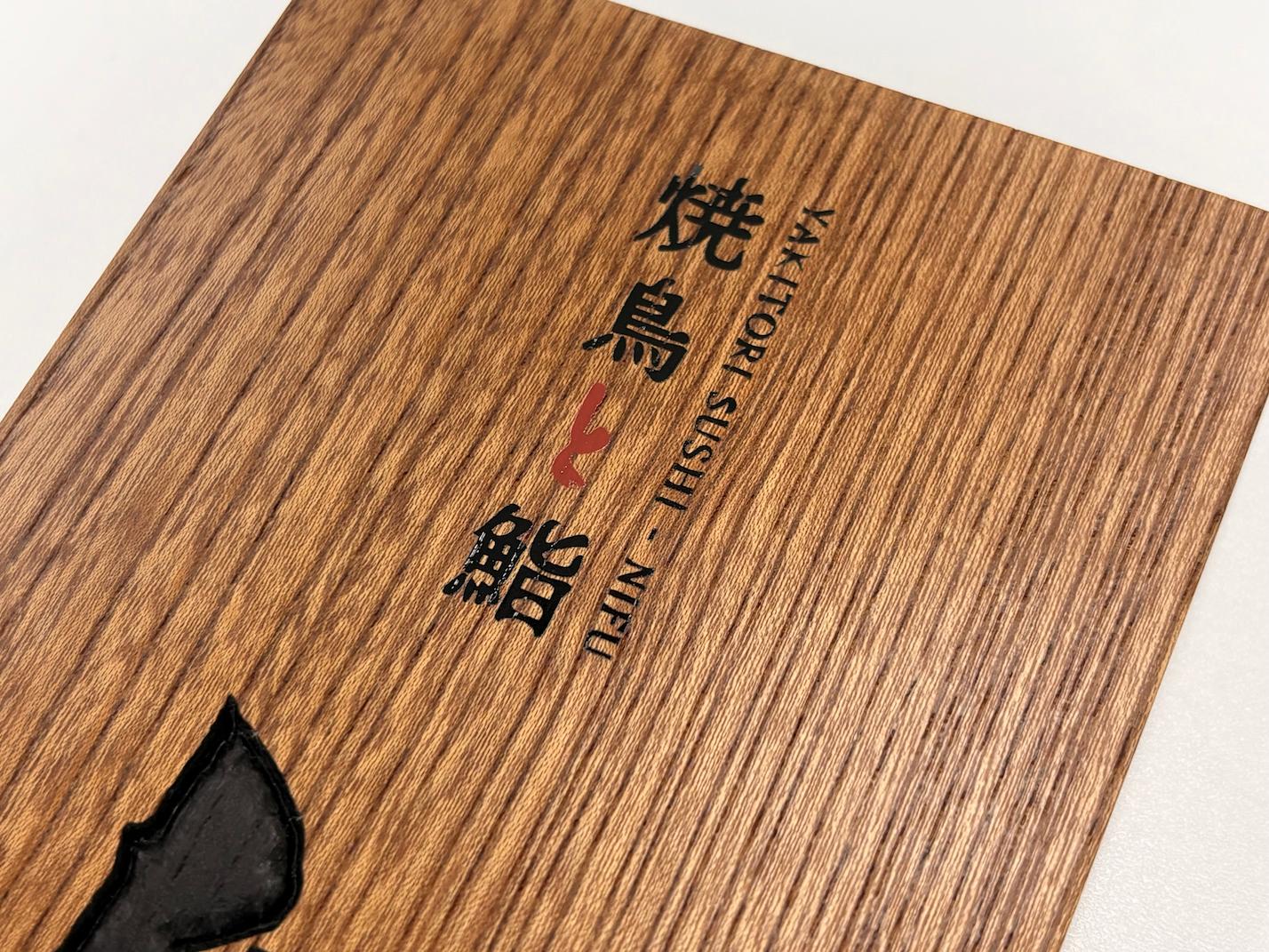 「焼鳥と鮨 にふ」様の、店舗木看板・木製彫り文字表札へのシルク印刷施工をさせていただきました。2